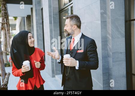 Arab Muslim Hispanic Business people working partner talking together during coffee break. Stock Photo