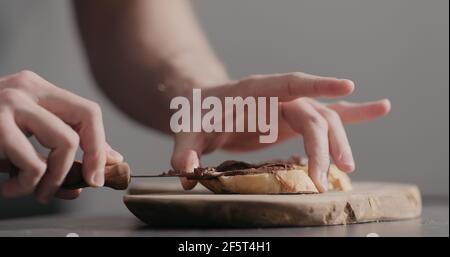 Man spreading chocolate hazelnut spread on baguette slices, wide photo Stock Photo