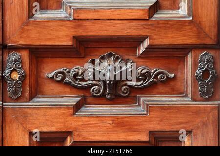 Decorative element. Ancient iron cast decor on a wooden door in the form of a bird and floral curl. Volterra. Italy. Stock Photo