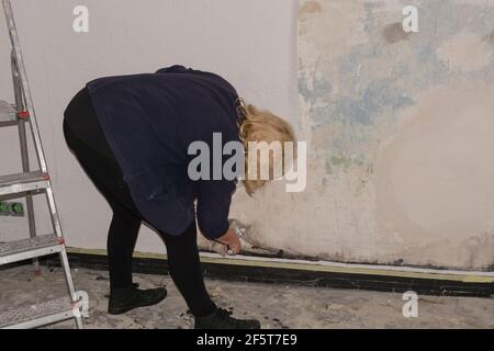 Glue wallpapers at home. Woman, worker puts wallpapers on the wall. renovation concept Stock Photo