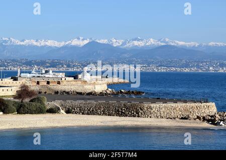 France, Antibes, the Gravette beach is nestled between the ramparts and the port Vauban, witn a magnificent background on the snowy Mercantour massive Stock Photo