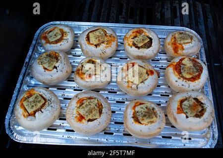 Stuffed portobello mushrooms stuffed with mozzarella and gorgonzola cheese and aromatic herbs on a black background, top view. Vegetarian food Stock Photo
