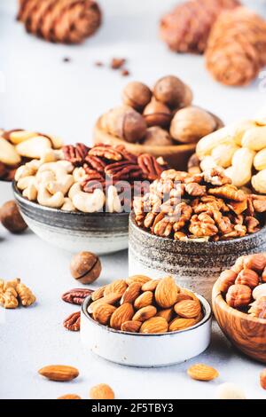 Assortment of nuts in bowls. Cashews, hazelnuts, walnuts, pistachios, pecans, pine nuts, peanuts, macadamia, almonds, brazil nuts. Food mix on gray ba Stock Photo
