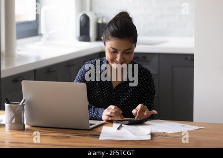 Close up smiling Indian woman using calculator and laptop Stock Photo