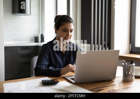 Close up focused Indian woman looking at laptop screen Stock Photo
