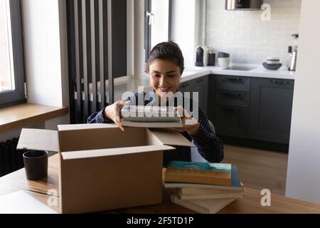 Smiling Indian young woman unpacking parcel with internet order Stock Photo