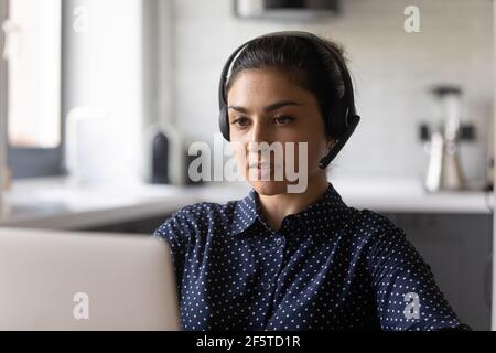 Close up serious confident Indian woman wearing headset using laptop Stock Photo
