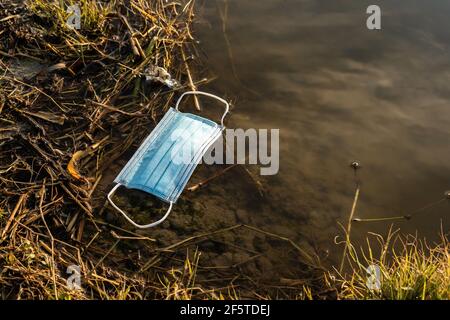 From above of plastic medical mask floating on water of pond showing concept of environmental pollution with plastic Stock Photo