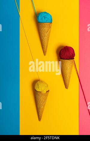 Colorful woolen thread balls in natural crunchy cones representing various gelato on three color background