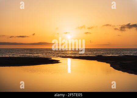 Scenic view of vivid orange sunset sky over calm sea water in evening Stock Photo