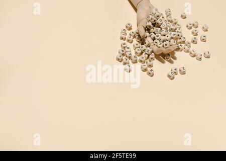 Top view of wooden hand with pile of alphabet letters on cubes scattered on beige background in studio Stock Photo