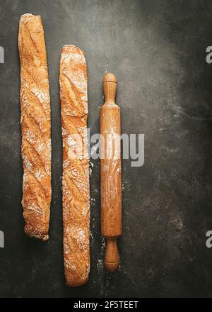 Two baked loaves of bread placed on empty wooden shelves with flour of ...