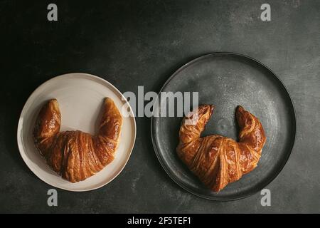Top view composition with appetizing freshly baked crusty croissants served on white and black plates on table Stock Photo