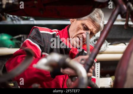 Senior male mechanic repairing old rusty disassembled motorbike while working in professional workshop Stock Photo