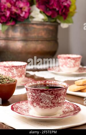 Ornamental ceramic cups with coffee served on table with flowers for teatime in cozy room at home Stock Photo