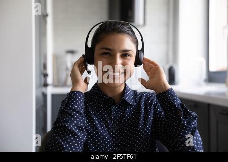 Head shot portrait smiling Indian woman wearing headset working online Stock Photo