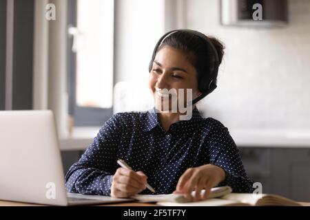 Smiling Indian woman wearing headset involved in online lesson Stock Photo