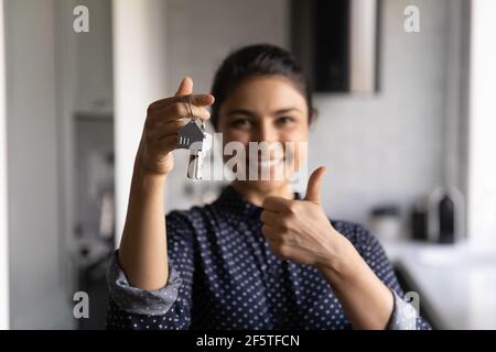 Close up overjoyed Indian woman holding keys, showing thumb up Stock Photo