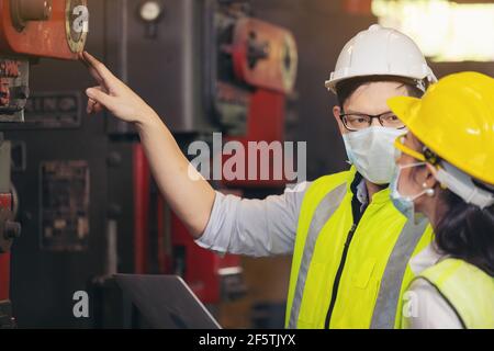 Two engineer in hard hat wearing safety using laptop for planning a project. Foreman explaining machinery to female employee Stock Photo
