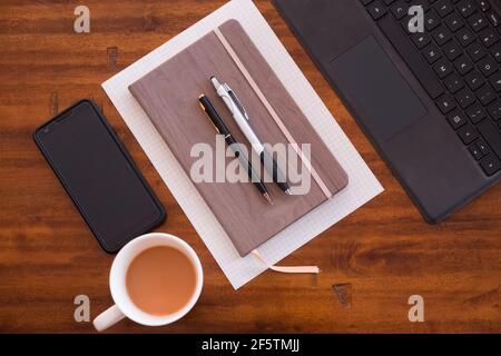 Working from home or at cafe or at the office. Computer, mobile device, smartphone, notebook, coffee and pens. Work anywhere. Working hard. Programmer Stock Photo