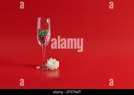 with round candies a glass stands on a red background with round candies  Stock Photo