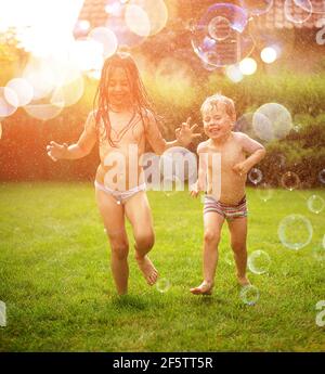 Joyful kids enjoying the summer shower in the garden Stock Photo