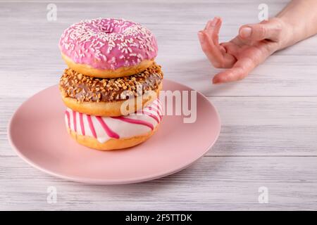 A hand reaches for three sugar-covered donuts Stock Photo