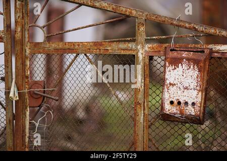 old rusty mailbox hanging on a rural fence mesh with newspaper. Stock Photo
