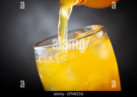 soft drink, pouring orange soda into glass on dark background Stock Photo