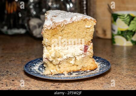 Extra huge large slice of Victoria sponge cake filled with cream on a plate topped with icing sugar, which is a comfort food and not recommended for a Stock Photo