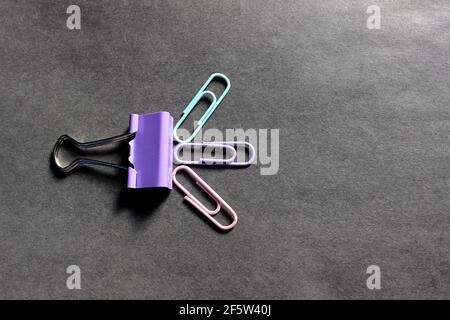 Multicolored paper clips on a dark background Stock Photo
