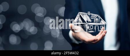 Real estate offer. Businessman holds an artificial model of the house Stock Photo