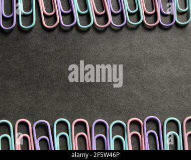 Multicolored paper clips on a dark background Stock Photo