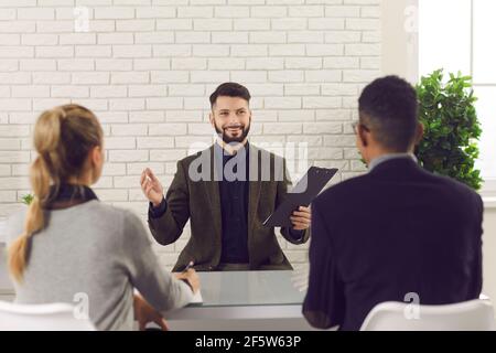 Happy job candidate telling about his experience in an interview with HR managers Stock Photo