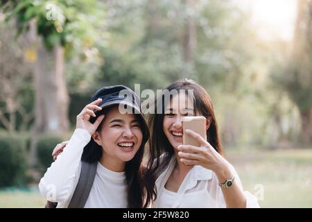 Happy two young attractive asian girls take a selfie at the park Stock Photo