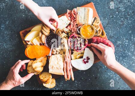 Charcuterie board. Cheese platter: Parmesan, caciocavallo, camembert and other with prosciutto, salami, fruits and nuts. Assortment of tasty appetizer Stock Photo