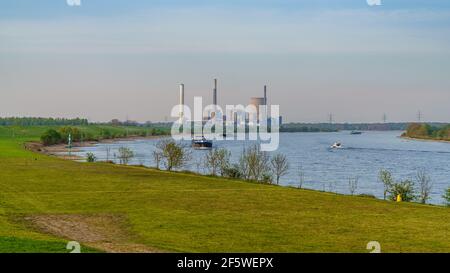 Rheinberg, North Rhine-Westphalia, Germany - April 16, 2020: View at the River Rhine in Orsoy, with the Voerde power station in the background Stock Photo