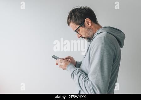 Face profile portrait of casual mid-adult male person using mobile smart phone indoors, selective focus Stock Photo