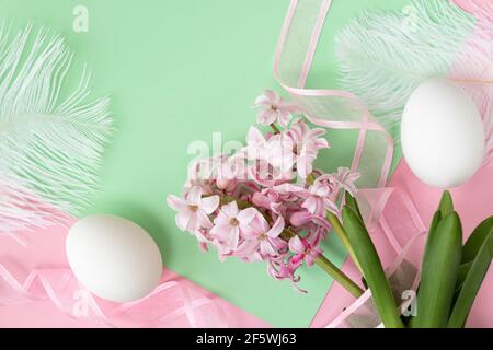 Two white egg, pink hyacinth flowers with pink ribbon on pastel green and pink colors. Happy Easter concept. Easter background. Top view Stock Photo
