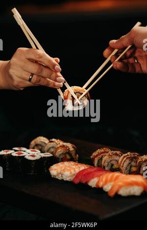 Man and woman pick up sushi with chopsticks at the same time Stock Photo