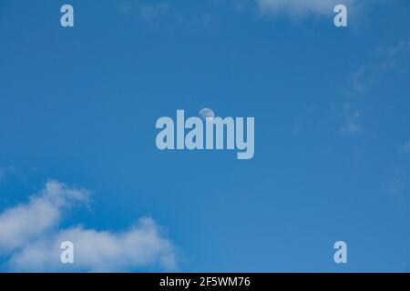day time moon against bright blue sky Stock Photo