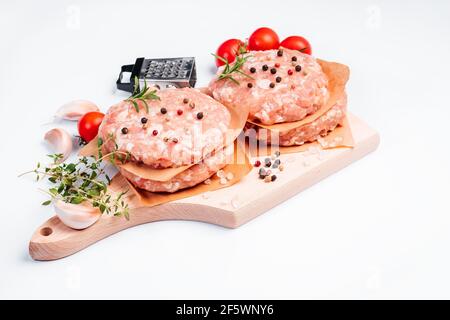 Chicken hamburgen on a wooden board with a branch rosemary and black pepper,tomatoes, place for text.Fast food for home and restaurants.Semi-finished Stock Photo