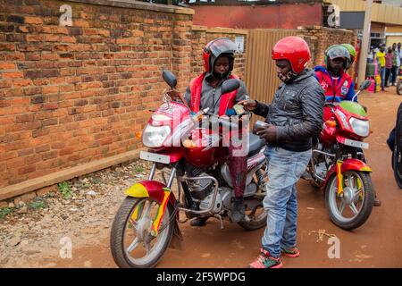 Kigali, Rwanda. 23rd Mar, 2021. Female moto-taxi rider Claudine Nyirangirente waits as a passenger pays in Kigali, Rwanda, March 23, 2021. TO GO WITH 'Feature: Rwanda's female motorcycle rider defies odds to join male-dominated job' Credit: Cyril Ndegeya/Xinhua/Alamy Live News Stock Photo