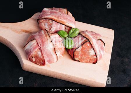 Three chicken hamburgers on a kitchen wooden board with basil leaves on a black background. Fast food. Convenience food, fast home cooking. Stock Photo