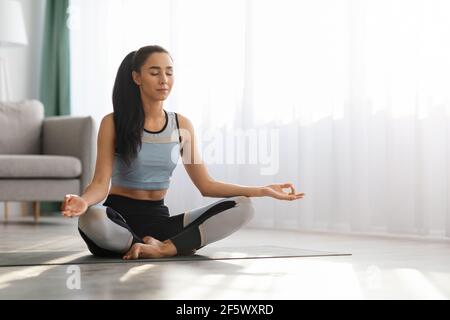 Young woman in sportswear meditating at home Stock Photo
