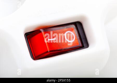 Red ON OFF switch on a simple electric appliance, button in off position, macro, extreme closeup. Turning off the power, saving energy, electrical bil Stock Photo