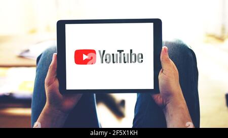 New York, USA - February 28, 2018: Youtube app logo on the tablet screen, selective focus on person's hands holding mobile device while watching video Stock Photo