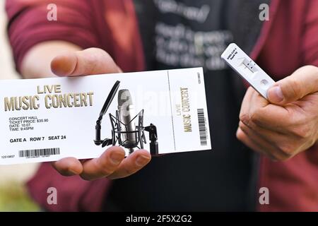 Concept for attending concerts during Corona Virus pandemic with hand holding ticket and SARS-CoV-2 rapid antigen test with negative result Stock Photo