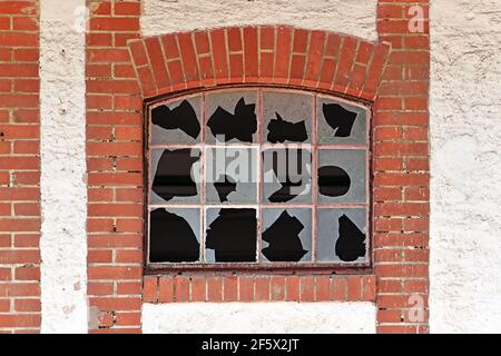 Old muntin window with broken glass of old abandoned building with red brick wall frame Stock Photo
