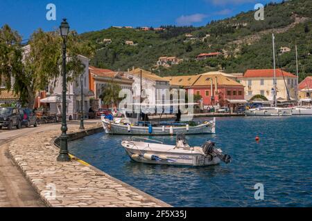 Paxos Island, Greece- May 7, 2019: view of beautiful Loggos Harbor - sea bay with calm turquoise water, boats and yachts colorful old houses, blue sky Stock Photo